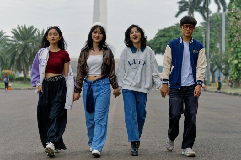 Four young adults walking outdoors, showcasing casual street fashion.